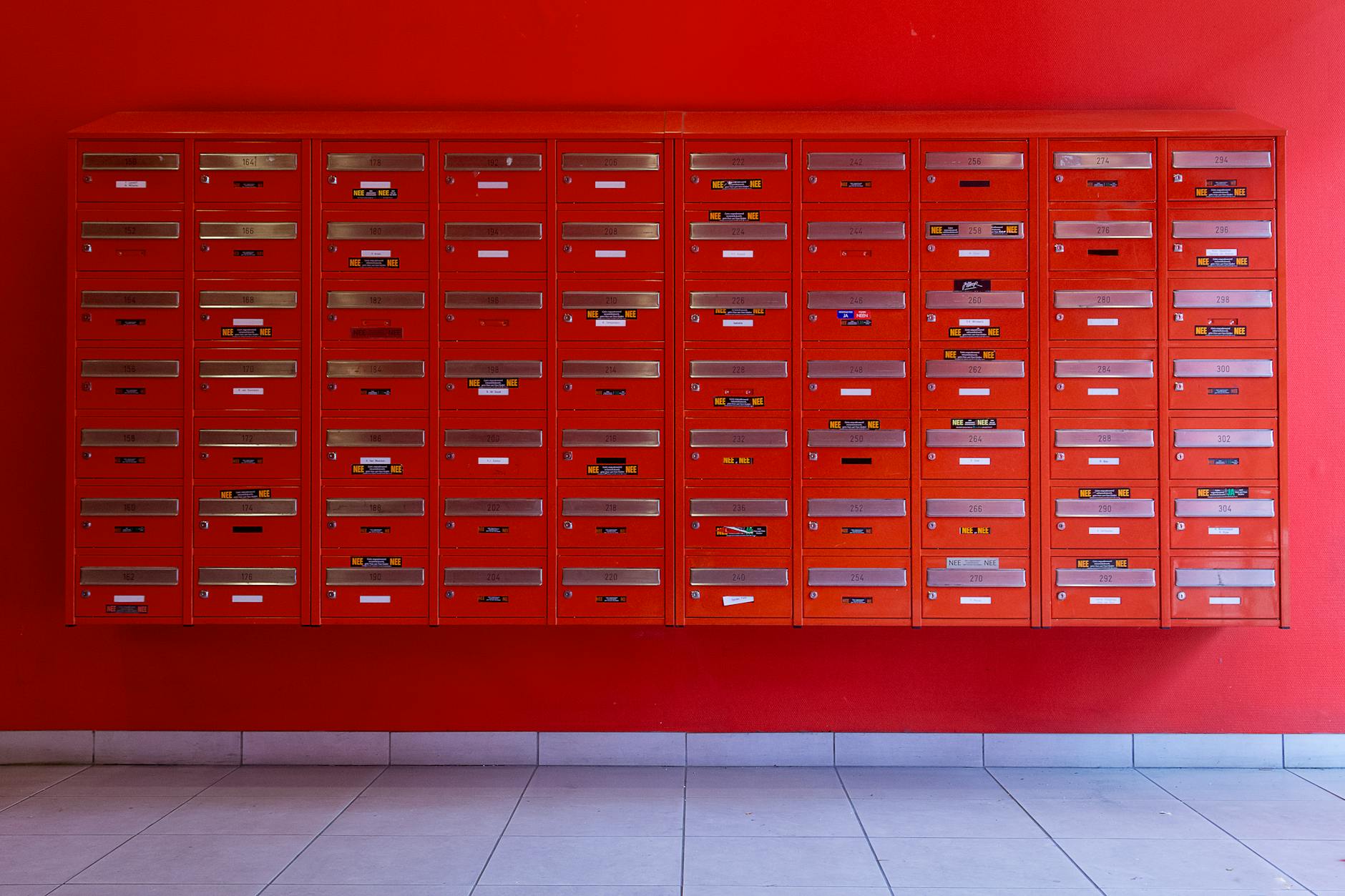 A vibrant wall of red mailboxes in an urban building, ideal for residential or commercial use.